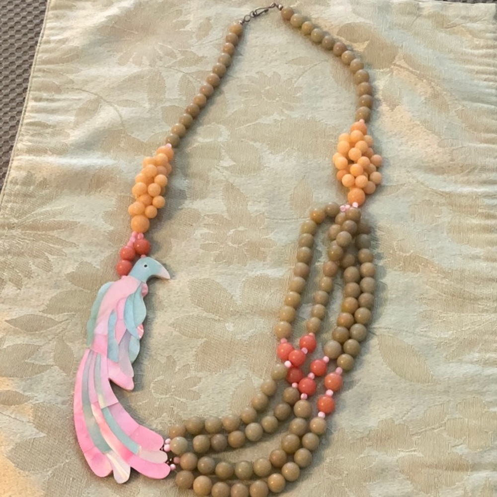 Pink and green beaded necklace with a tropical bird made out of cut glass.